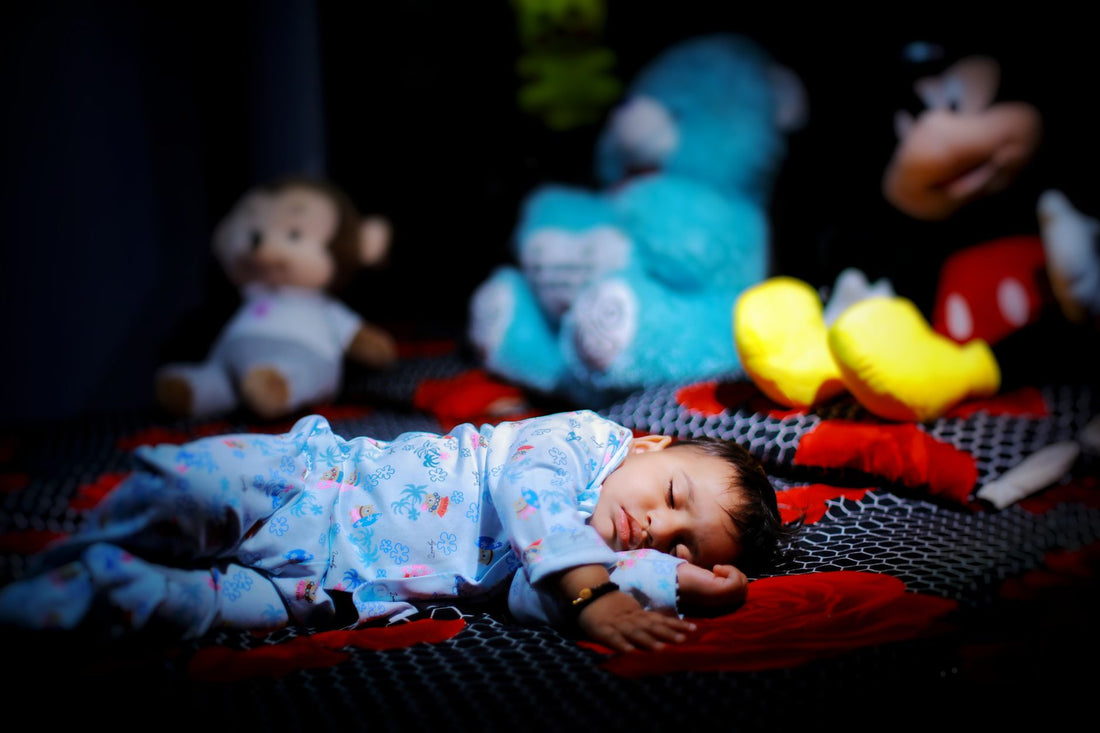 Bébé qui dort paisiblement la nuit entouré de peluches