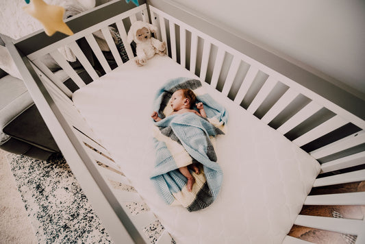 Bébé enveloppe dans une couverture bleue dormant dans son berceau
